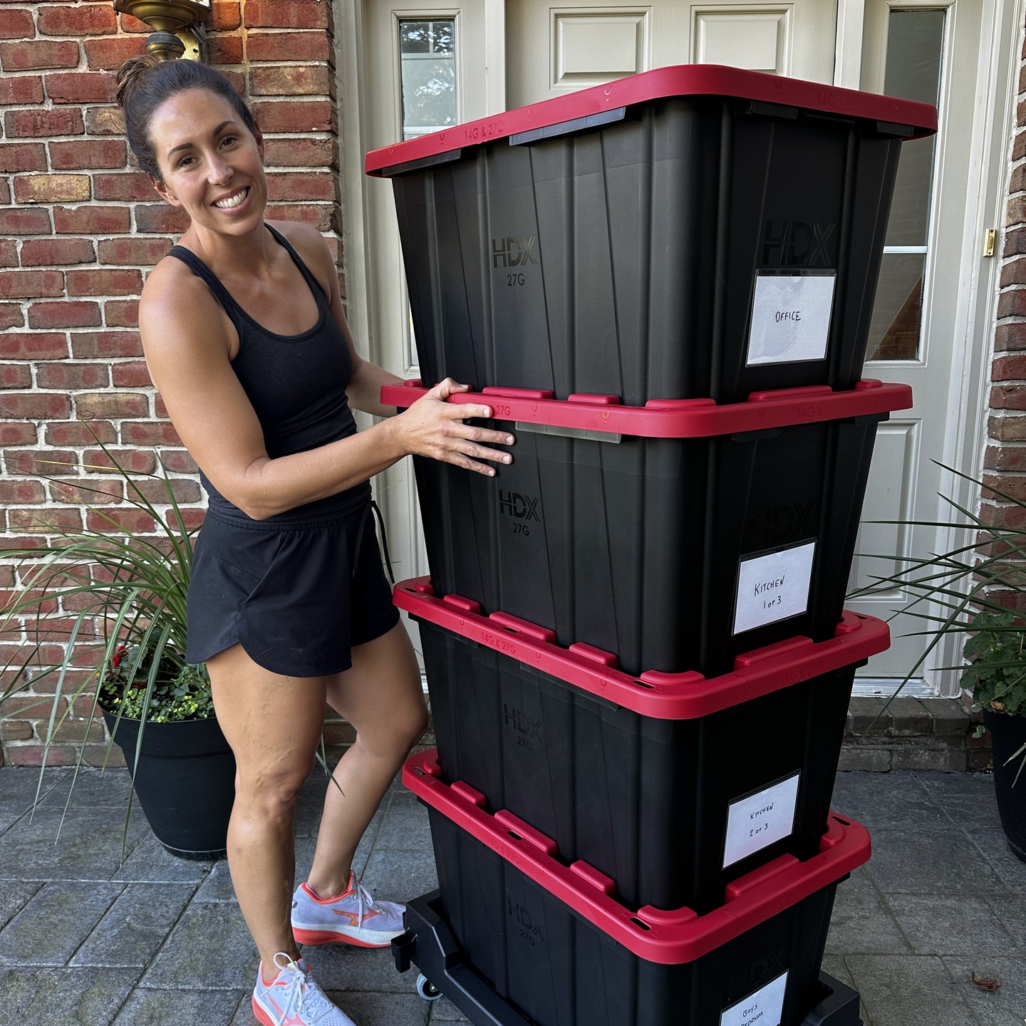 Stack of four labeled moving totes on a dolly beside a front door